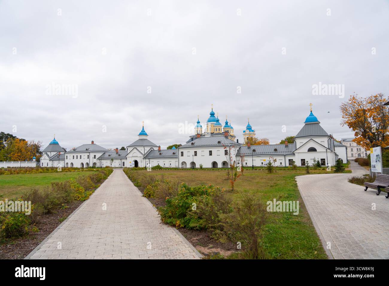 Une large vue panoramique sur tout un monastère orthodoxe avec ses murs blancs et ses dômes bleus, avec un long chemin pavé menant le regard du spectateur Banque D'Images