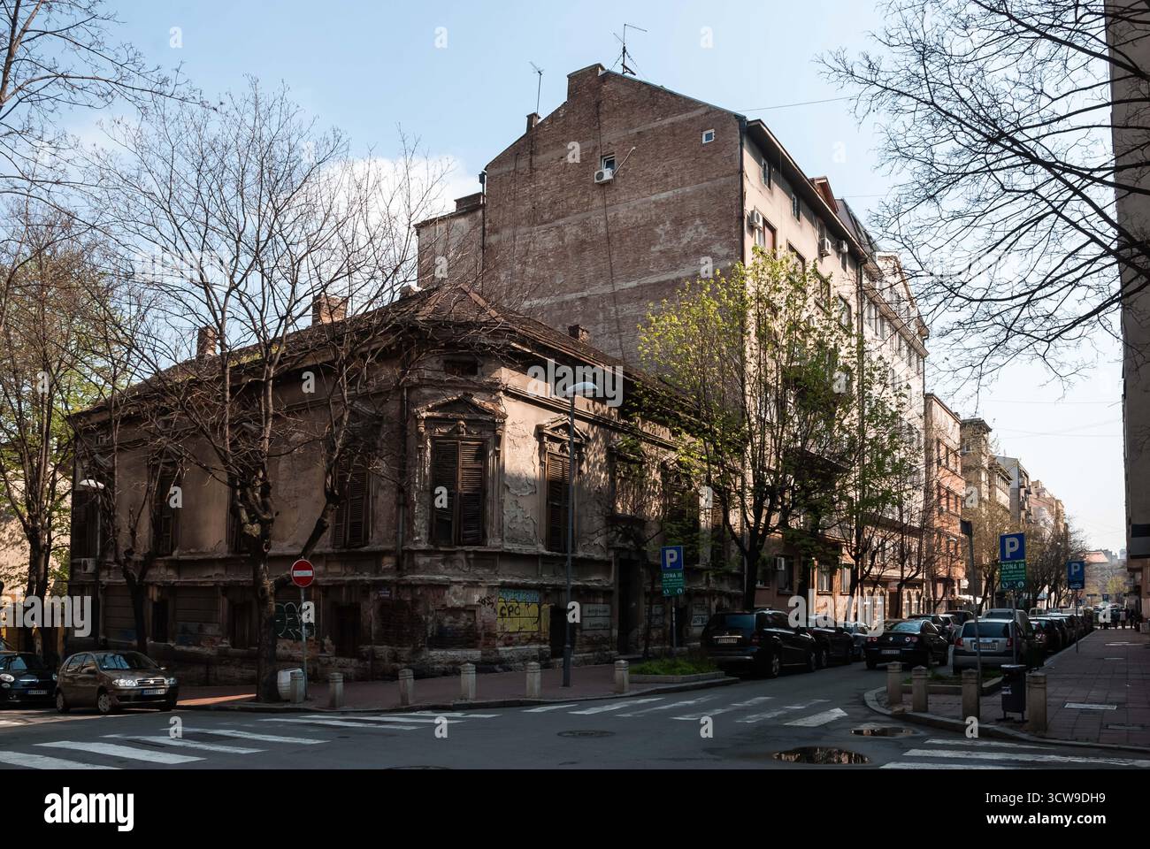 Belgrade, Serbie - 29 mars 2014 - bâtiment délabré au coin de la rue urbaine avec briques apparentes et voitures à proximité. Banque D'Images