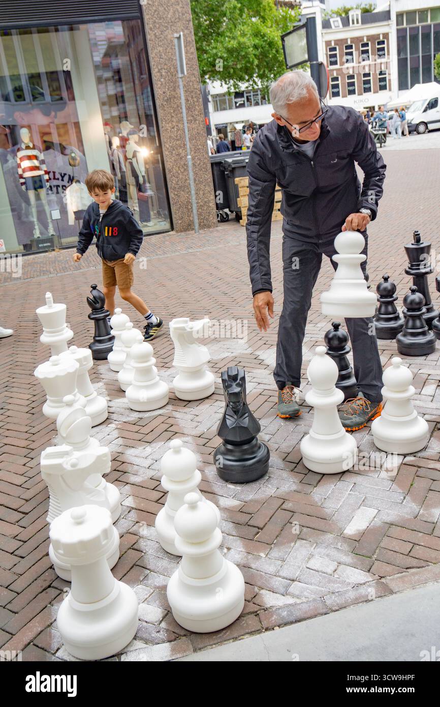 grand-père avec son jeune petit-fils jouant aux échecs en plein air avec de grandes pièces d'échecs Banque D'Images