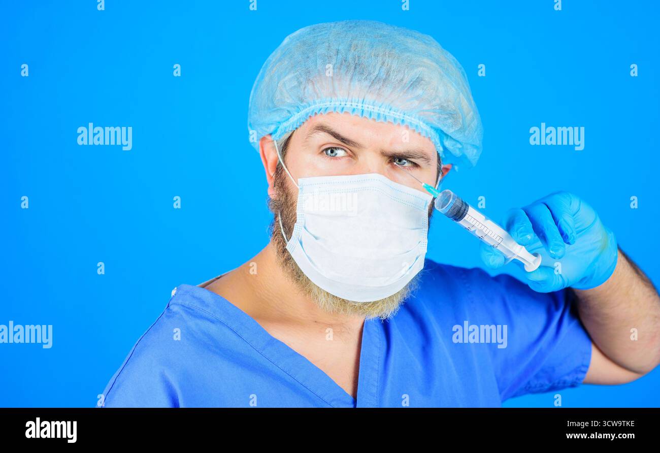 Docteur en masque médical et uniforme avec seringue. Infirmier masculin en gants avec seringue. Personnel hospitalier. Docteur avec seringue, homme dans le masque médical préparation Banque D'Images