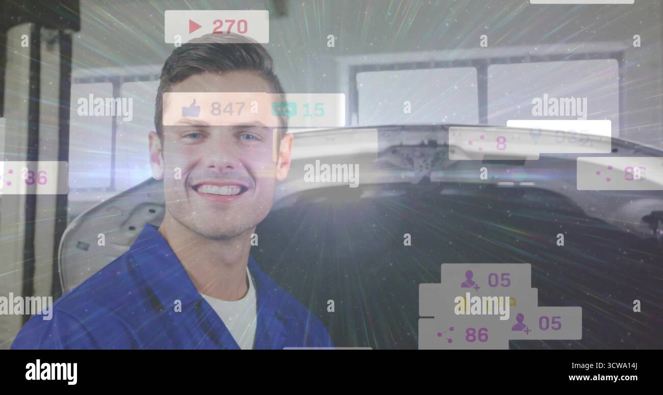 Mécanicien portant une combinaison bleue souriante dans un atelier de réparation, capot de voiture ouvert, superpositions de médias sociaux Banque D'Images