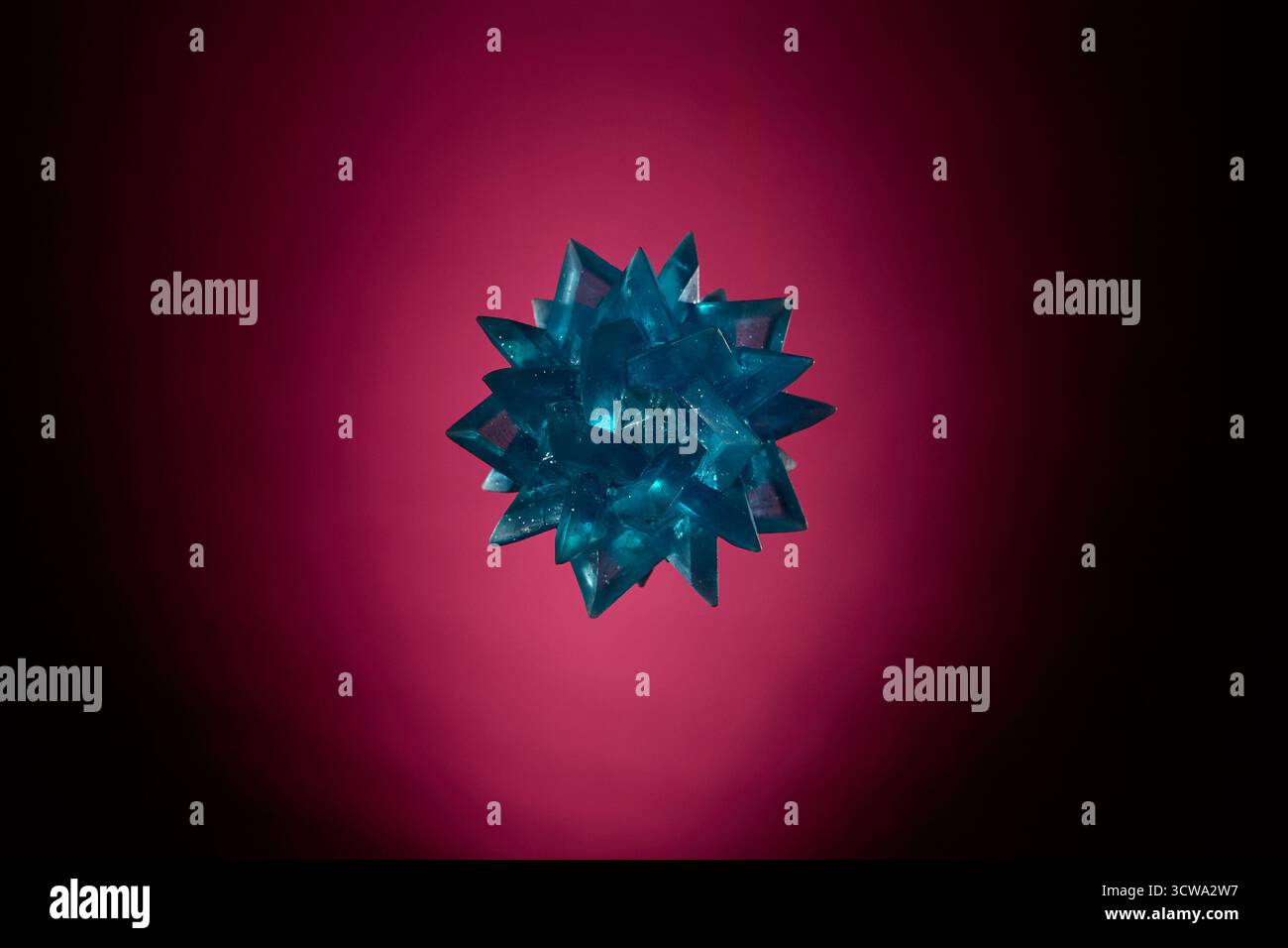 Photo de nature morte de boule de massage épi bleu sur fond dégradé rouge. Concept de thérapie, sport et accessoires de bien-être sous studio créatif Banque D'Images