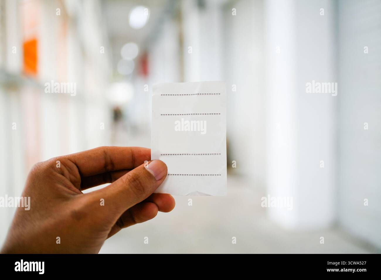 Gros plan de la main tenant un morceau de reçu en papier thermique vierge Banque D'Images