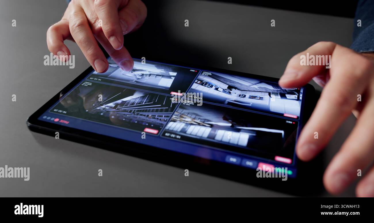 Les professionnels DE L'INFORMATIQUE masculine surveillent les vidéos de vidéosurveillance sur tablette à domicile. Banque D'Images