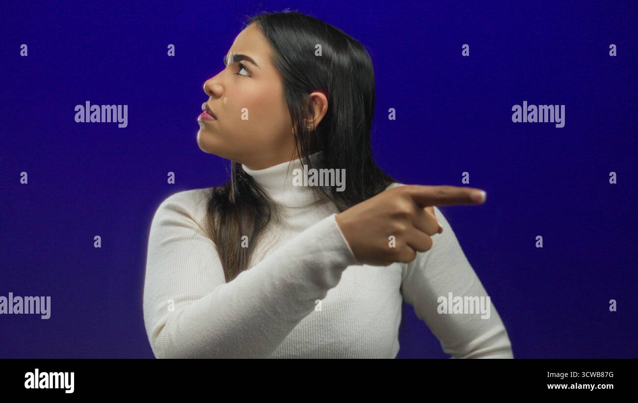 Le doigt d'une femme capturé sur un fond souligne l'identité jeune hispanique latine contre un mur bleu isolé. Banque D'Images