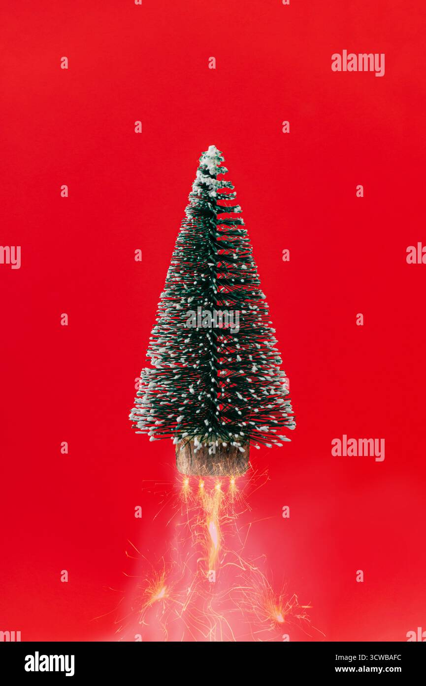 Arbre de Noël avec feux d'artifice sur fond rouge. Concept de compte à rebours minimal de Noël et du nouvel an. Fusée arbre de Noël. Aménagement créatif des fêtes. Banque D'Images
