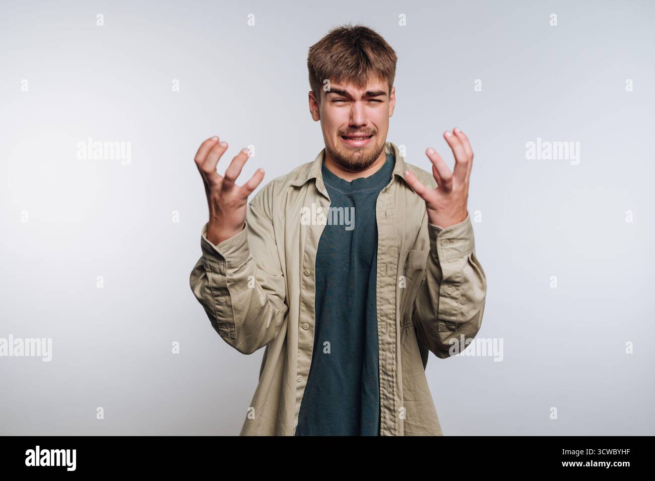 portrait d'un jeune homme éprouvant de la frustration, mettant en valeur un éclat émotionnel avec des expressions intenses sur fond blanc Banque D'Images