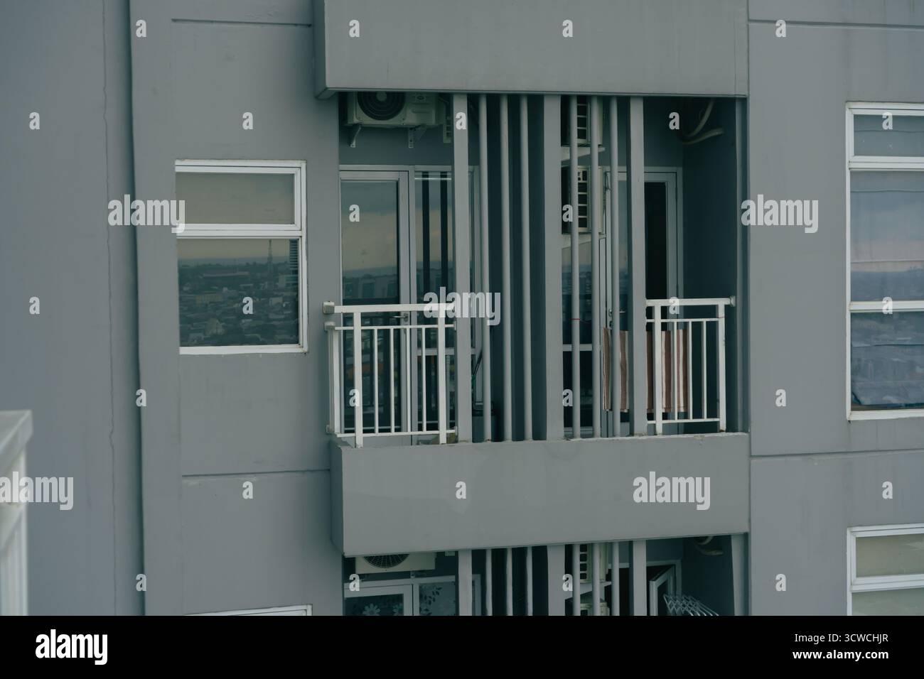 Vue extérieure d'un immeuble moderne d'appartements gris avec balcons et fenêtres donnant sur un paysage urbain Banque D'Images