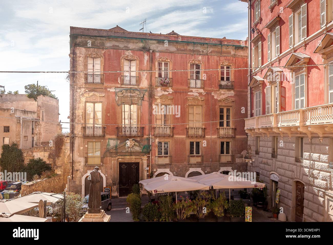 Palais historique sur la Piazza Carlo Alberto, quartier Castello, Cagliari, Sardaigne, Italie, avec façade rouge délavée et café en plein air ci-dessous Banque D'Images