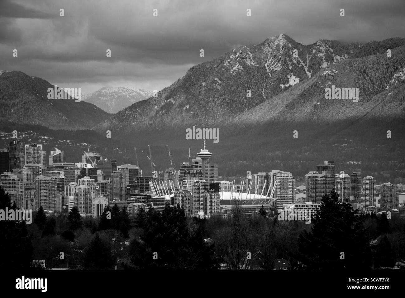 L'horizon de la ville de Vancouver est visible avec les montagnes environnantes sous un ciel nuageux, créant un contraste visuel saisissant. Banque D'Images