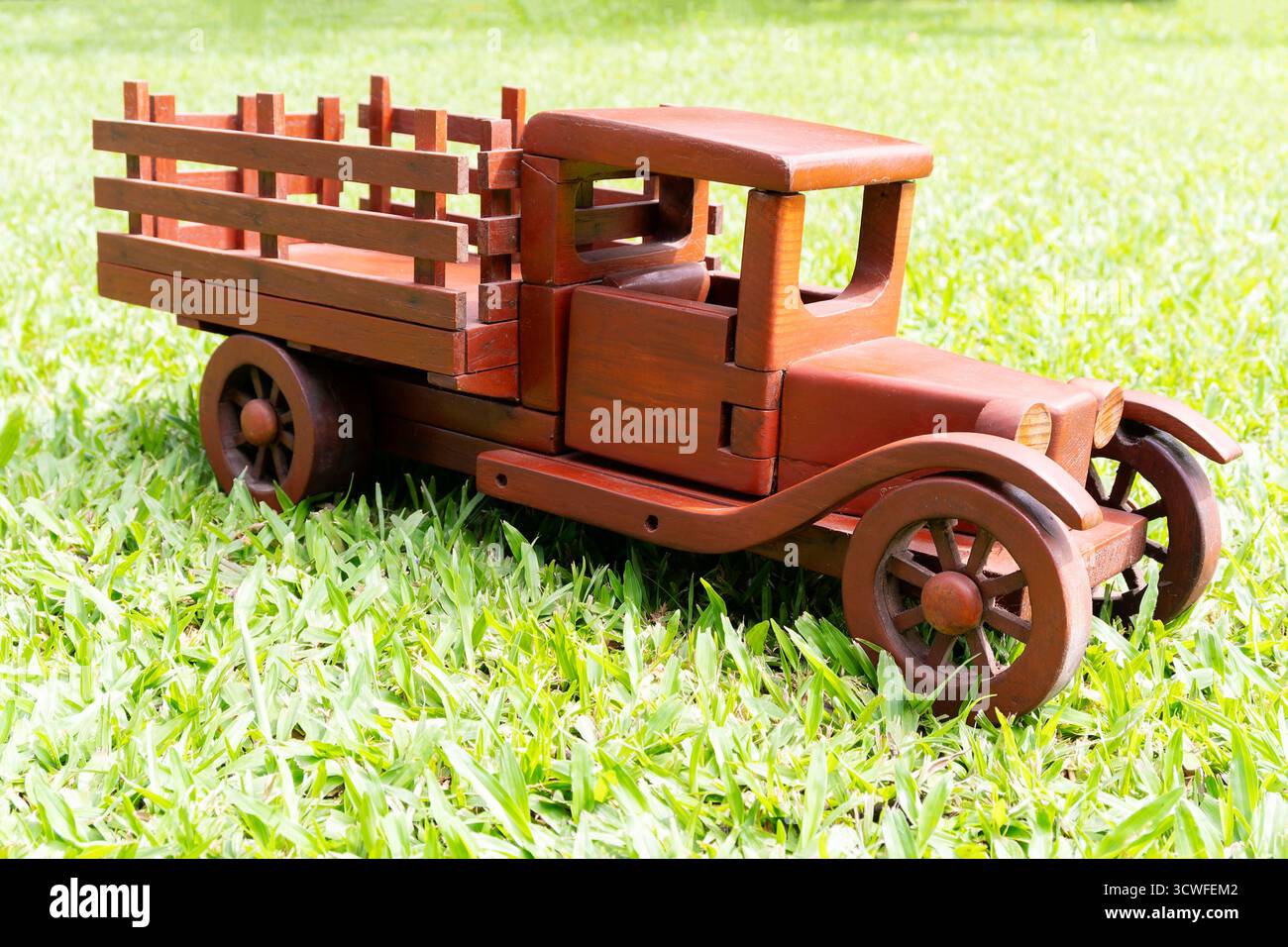 Photo en gros plan d'un camion jouet en bois fabriqué à la main placé sur de l'herbe vert vif. Le camion est conçu avec un style vintage, avec un plateau avec WO Banque D'Images