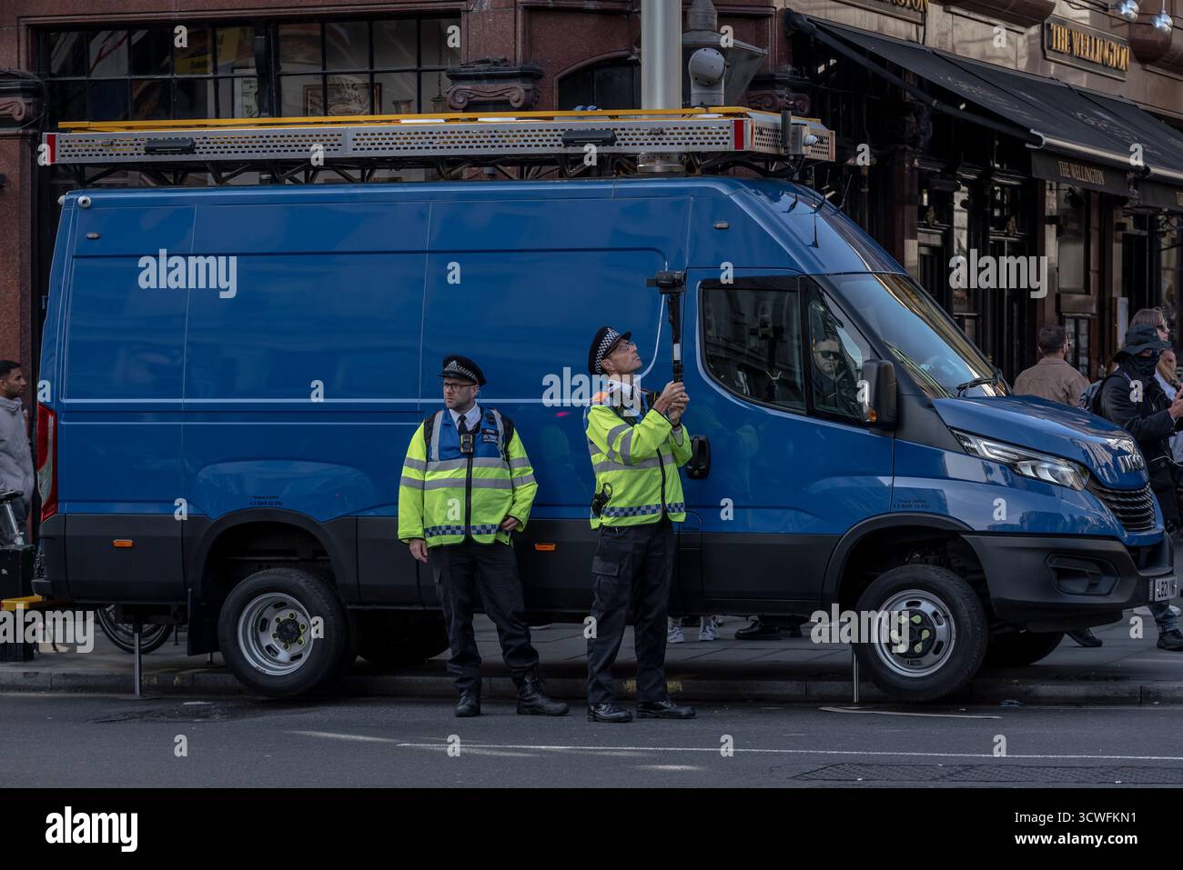 Londres, Royaume-Uni. 11 octobre 2025. (Photo) deux collecteurs de preuves de police se tiennent à côté d'un van de reconnaissance faciale met police, une unité mobile équipée de caméras et de logiciels pour effectuer une reconnaissance faciale en direct – qui implique la comparaison des visages capturés sur des images de caméra de surveillance avec une liste de surveillance de la police en temps réel. La police du met, la plus grande force de police de Grande-Bretagne, est actuellement en train de doubler son utilisation de la reconnaissance faciale en direct à 10 déploiements par semaine, contre quatre fois par semaine actuellement sur deux jours. Crédit : Guy Corbishley/Alamy Live News Banque D'Images