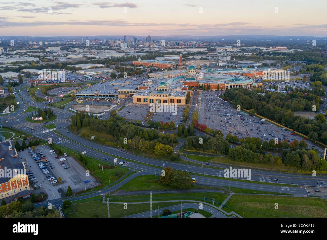 Vue aérienne du Trafford Centre et des routes environnantes avec Manchester skyline au crépuscule. Banque D'Images