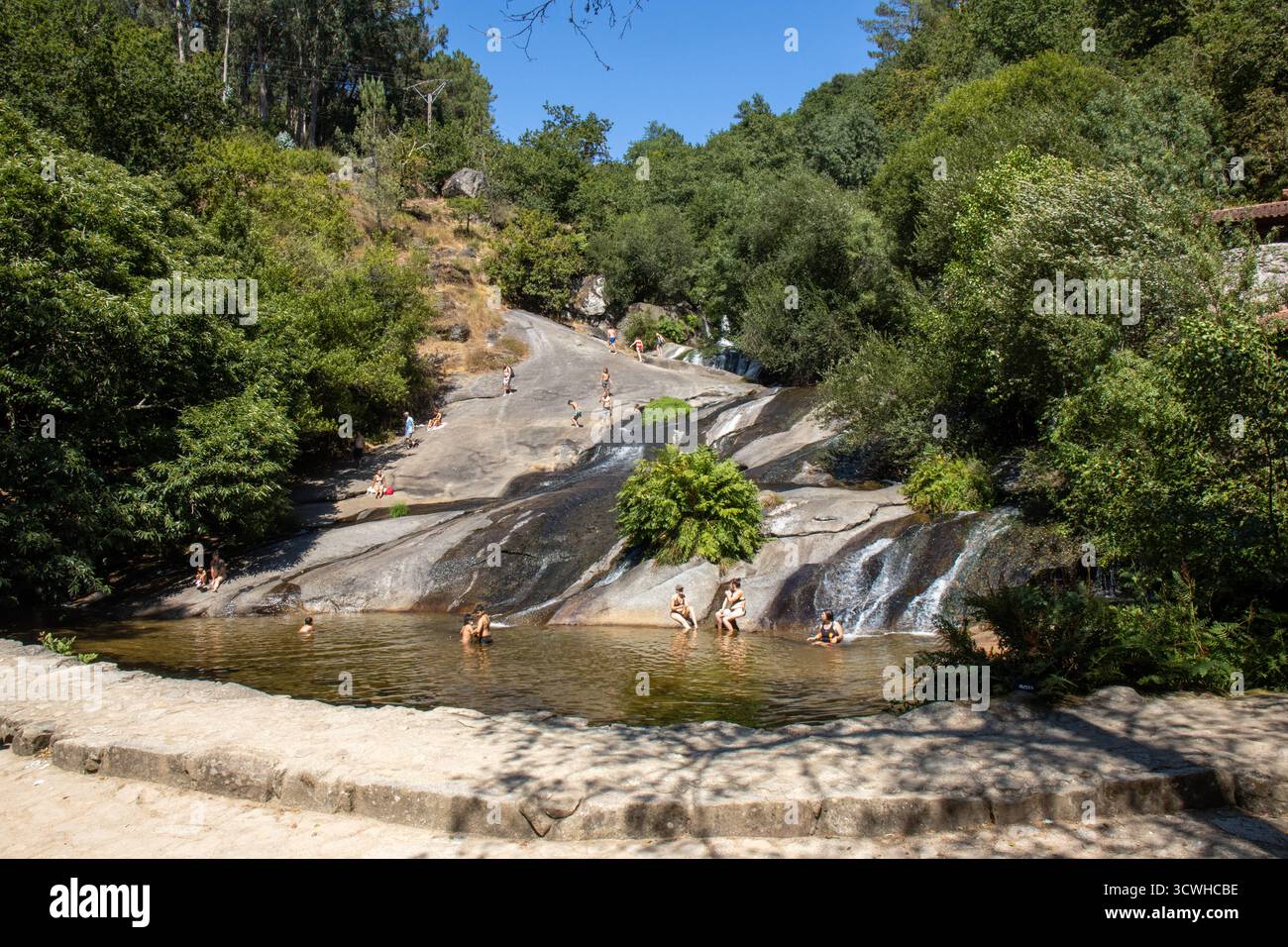 Vista panorámica de la cascada del Río Barosa con personas disfrutando del baño y el Agua deslizándose sobre rocas pulidas. Barro, Pontevedra, España Banque D'Images