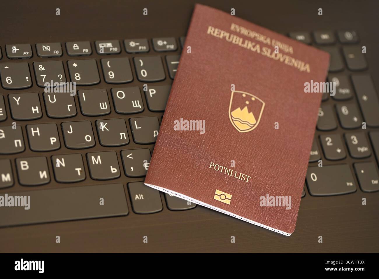 Passeport slovène se trouve sur fond noir de boutons de clavier d'ordinateur portable gros plan. Technologies et contrôle en Europe concept Banque D'Images