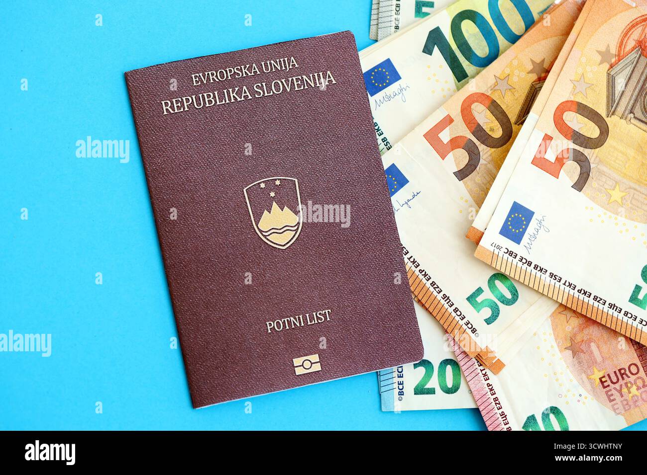 Le passeport slovène se trouve avec des billets de banque en euros sur fond bleu gros plan. Salaire et retraite en Europe concept Banque D'Images