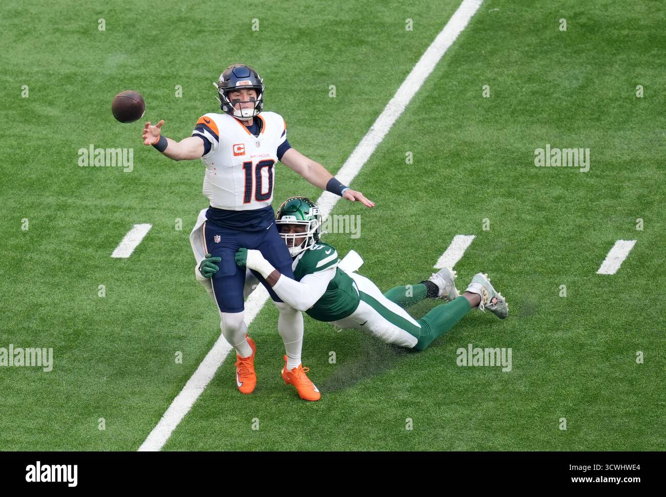 Bo Nix des Broncos de Denver (à gauche) est attaqué par Will McDonald IV des jets de New York lors du match international de la NFL au Tottenham Hotspur Stadium de Londres. Date de la photo : dimanche 12 octobre 2025. Banque D'Images