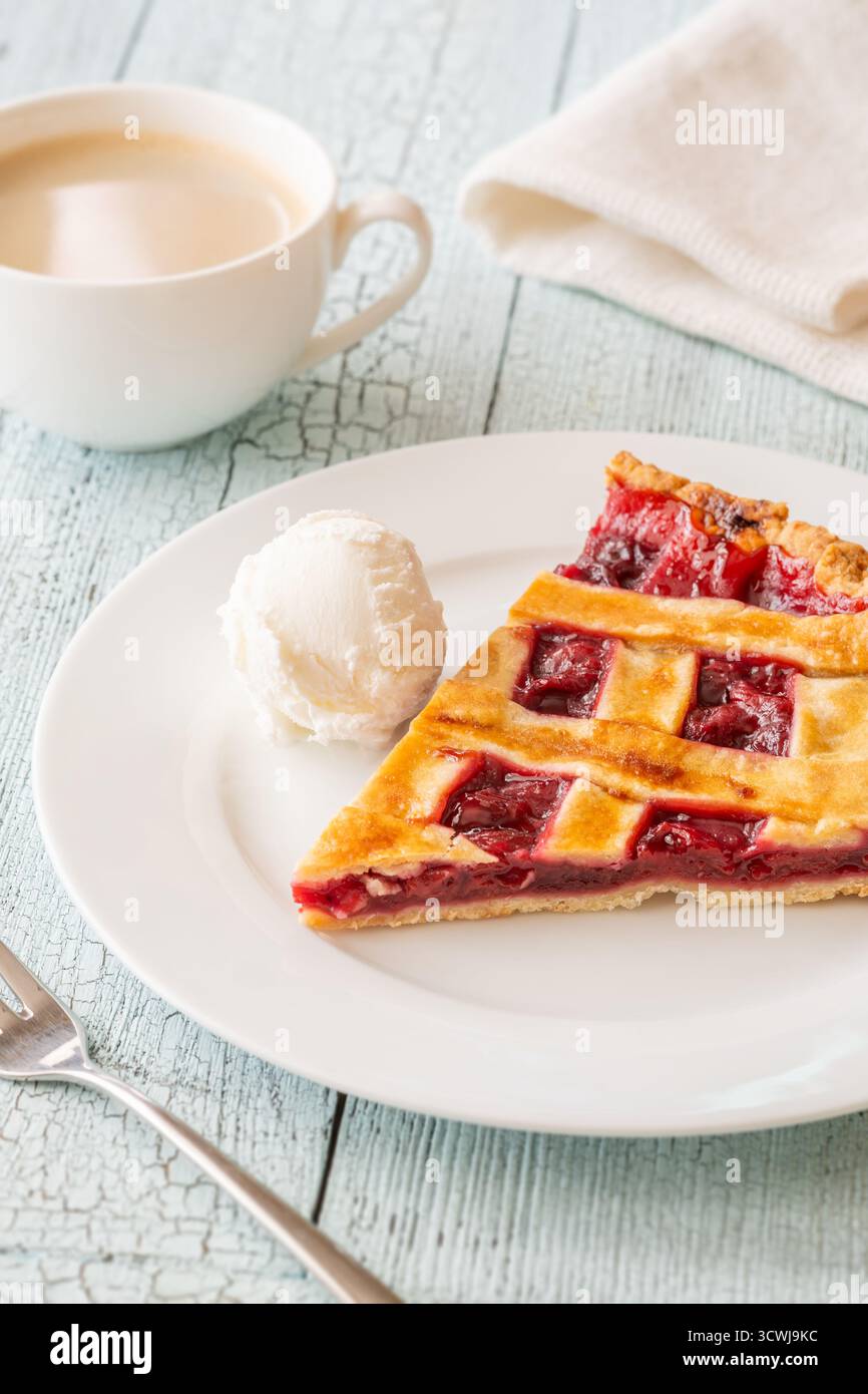 La tarte chaude et la crème glacée fraîche se marient parfaitement avec le café à la vapeur dans une lumière douce Banque D'Images
