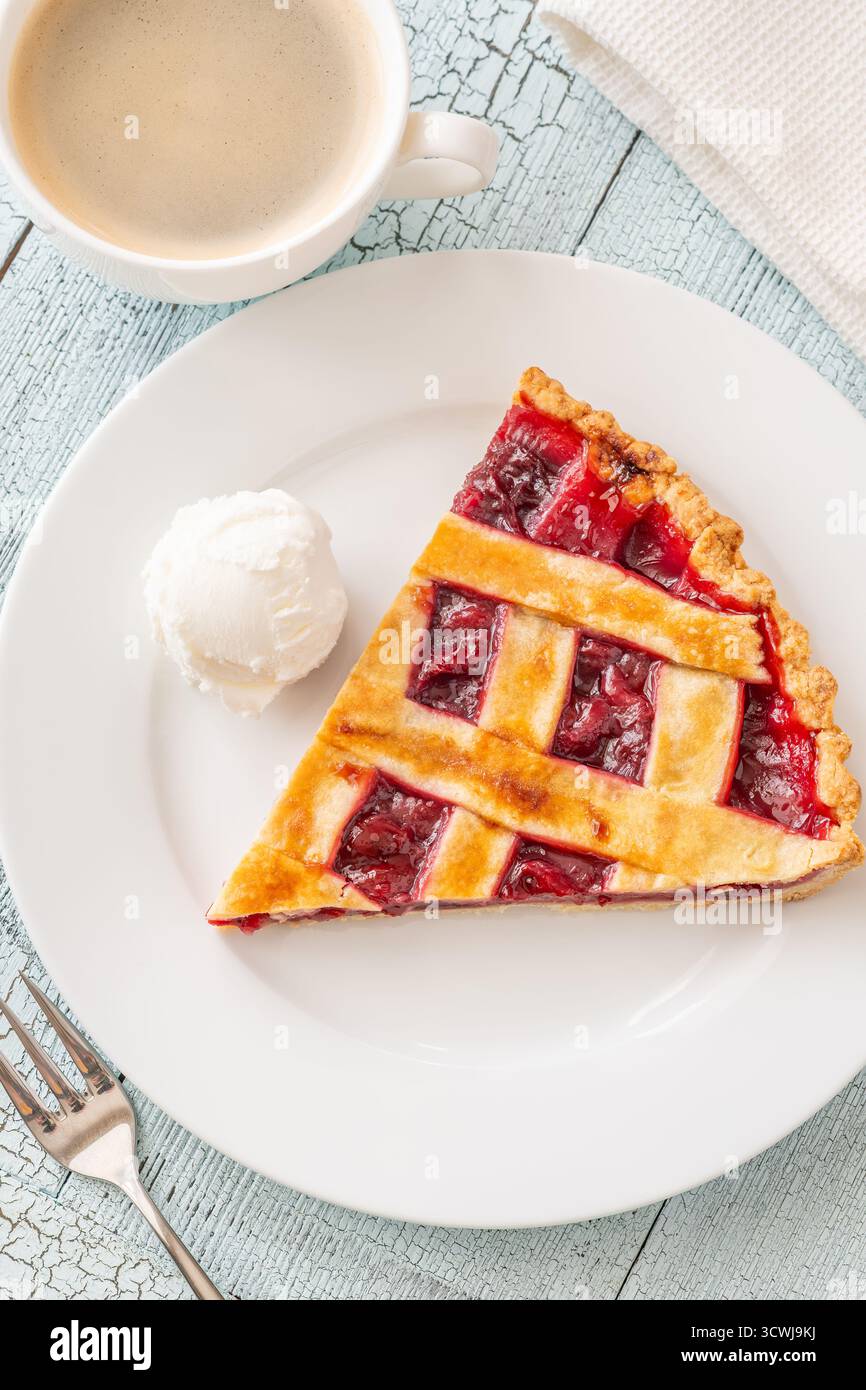 La tarte chaude et la crème glacée fraîche se marient parfaitement avec le café à la vapeur dans une lumière douce Banque D'Images