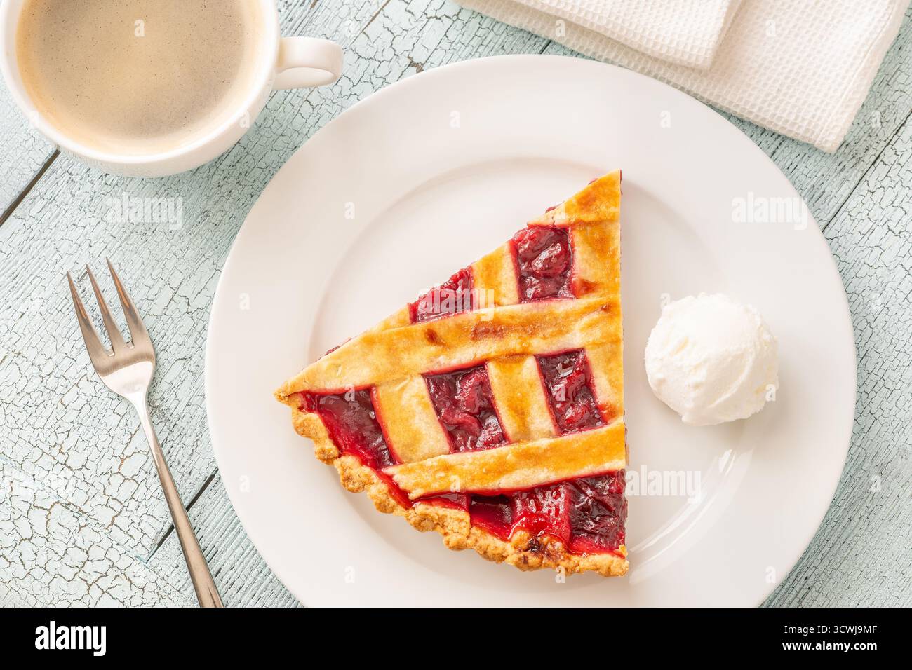 La tarte chaude et la crème glacée fraîche se marient parfaitement avec le café à la vapeur dans une lumière douce Banque D'Images