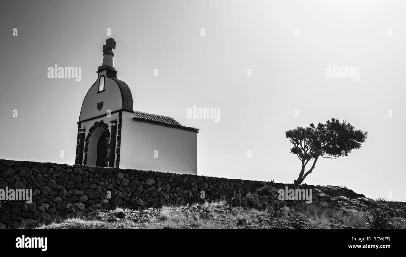 La chapelle sereine de San Isidro se dresse seule au sommet d'une colline, encadrée par un arbre solitaire dans une lumière douce, Alajero, la Gomera, Espagne Banque D'Images