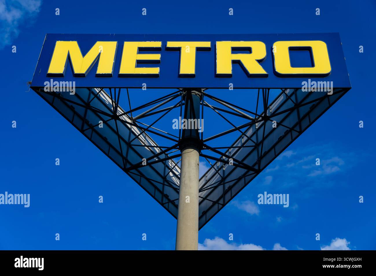 Panneau de magasin de gros Metro avec logo jaune sur fond de ciel bleu à Berlin, Allemagne, par une journée ensoleillée brillante Banque D'Images