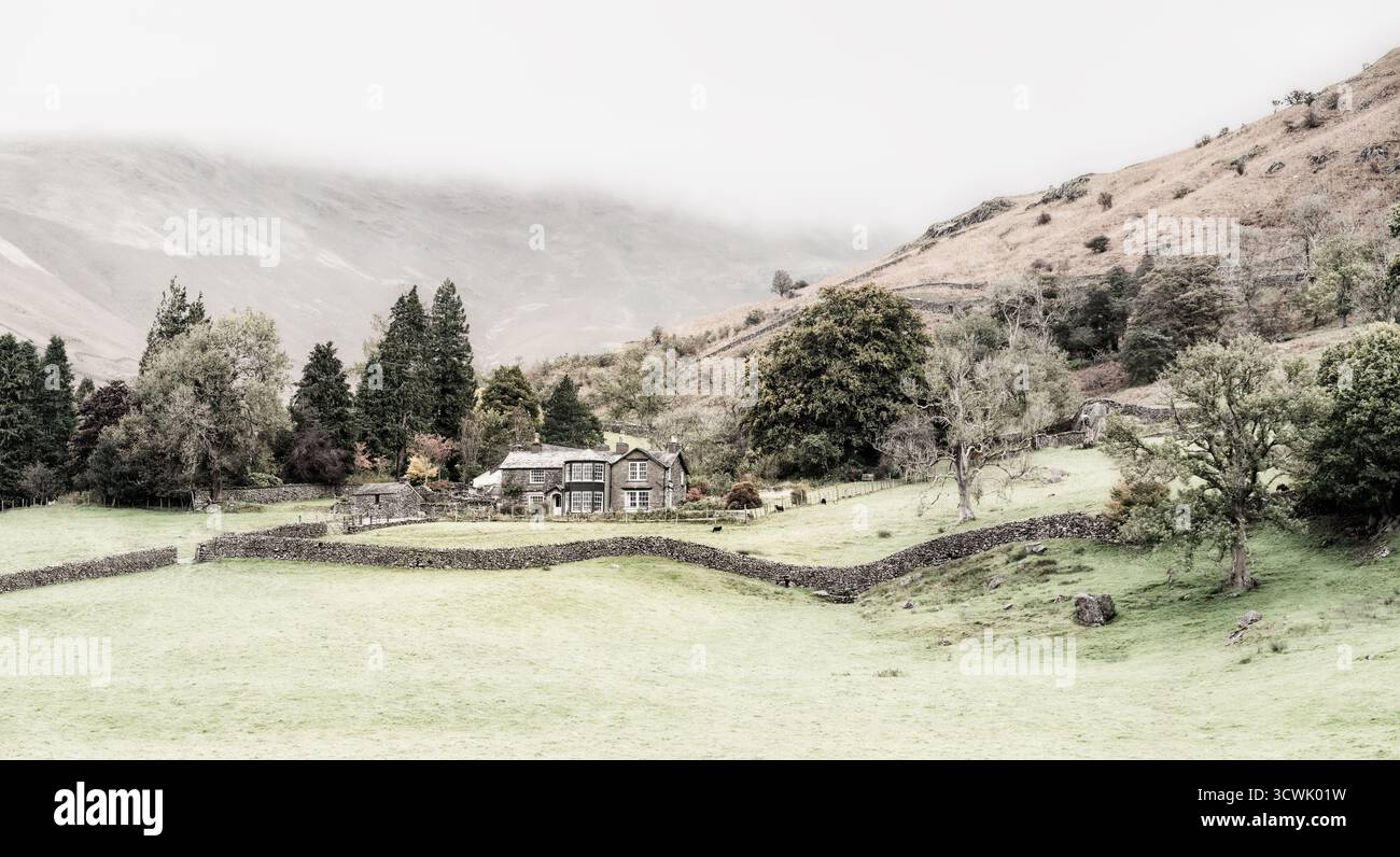 Un chalet pittoresque niché dans le Lake District, Royaume-Uni. Des murs de pierre divisent les champs verts, créant une scène paisible et rurale. Banque D'Images