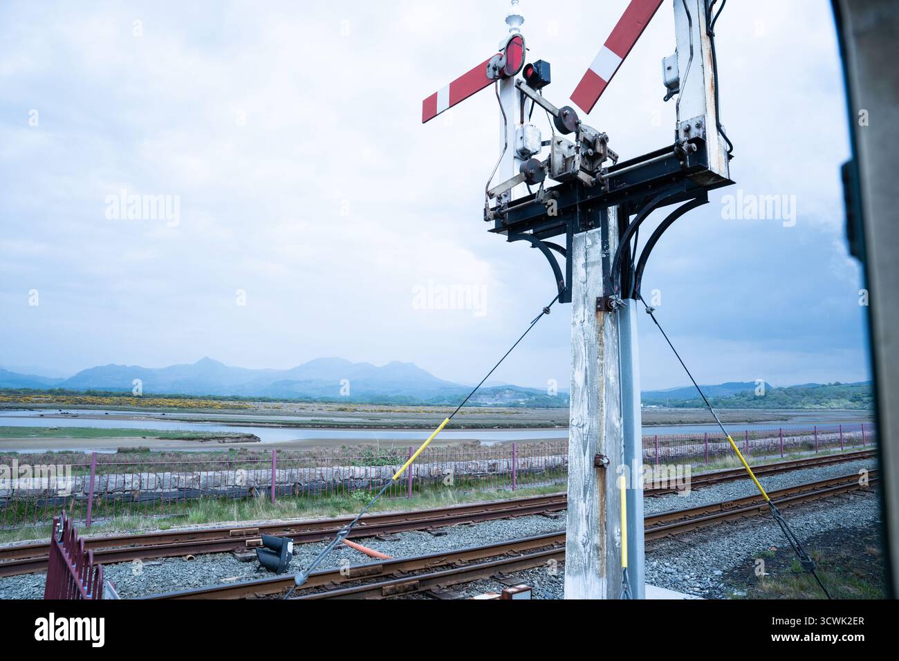 Signal sémaphore ferroviaire traditionnel à côté de la ligne de chemin de fer côtière avec des montagnes en arrière-plan Banque D'Images