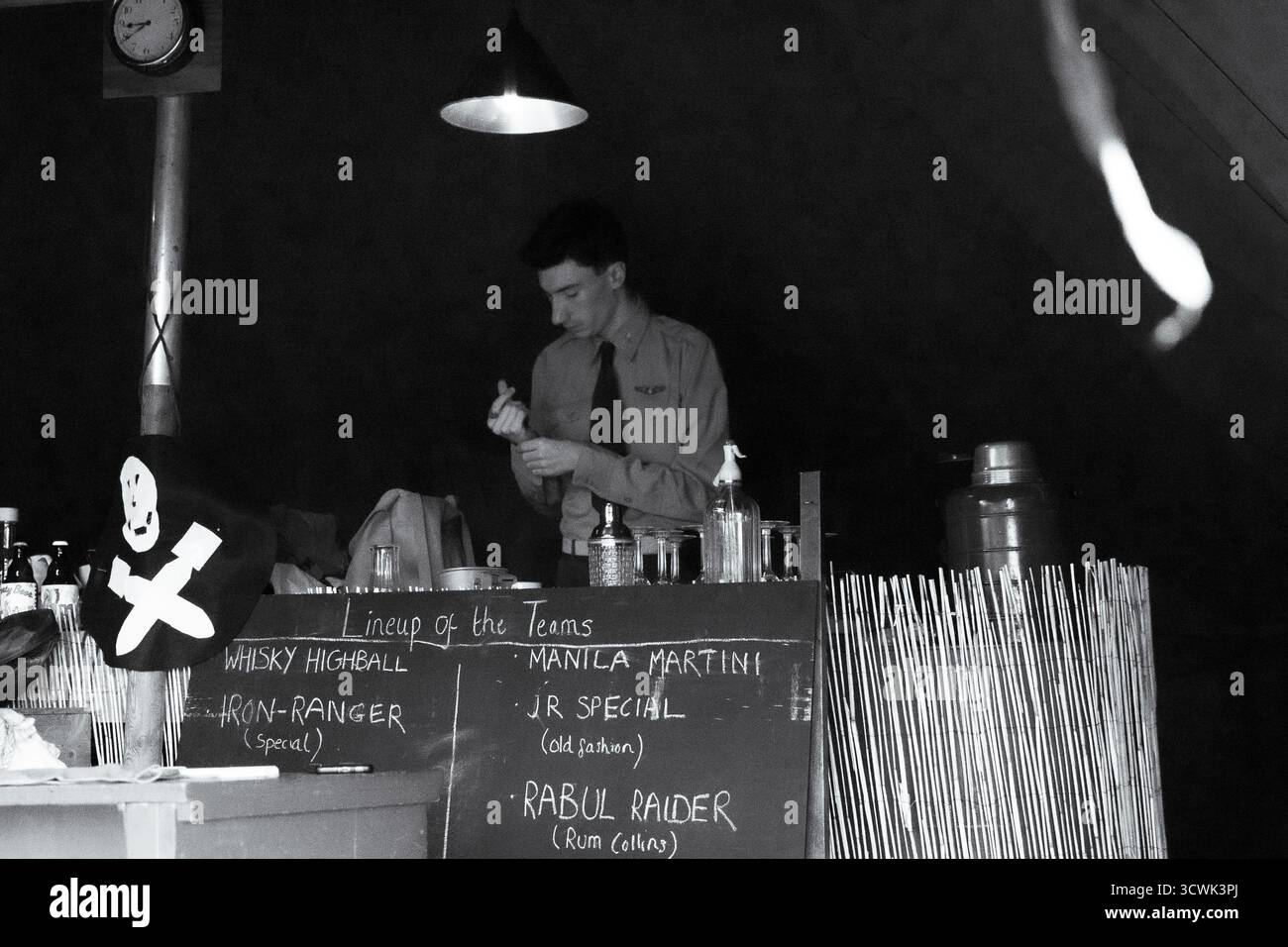 Officier de la RAF préparant des cocktails dans un bar sur le thème de la guerre avec un tableau de menu vintage Banque D'Images