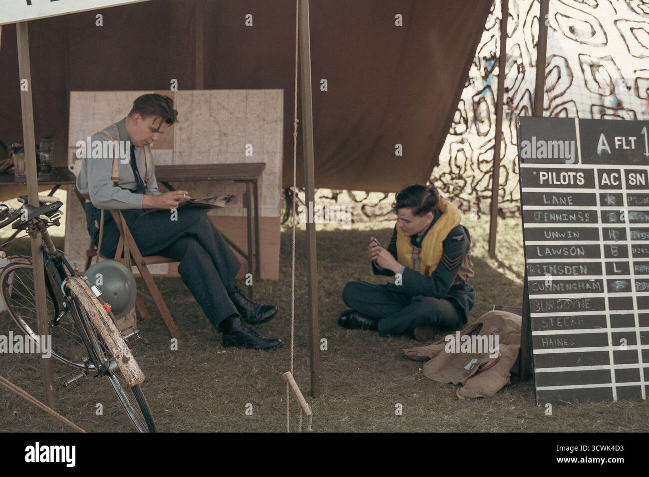 Pilotes de la RAF se relaxant à l'aérodrome de temps de guerre avec le tableau d'état de vol Banque D'Images
