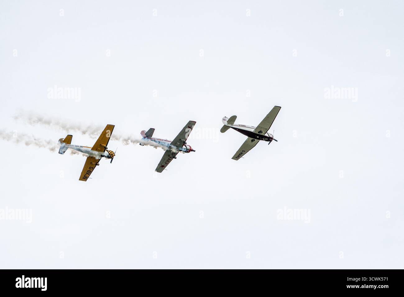 Trois avions d'époque effectuant des démonstrations acrobatiques avec des traînées de fumée au spectacle aérien de Duxford Banque D'Images