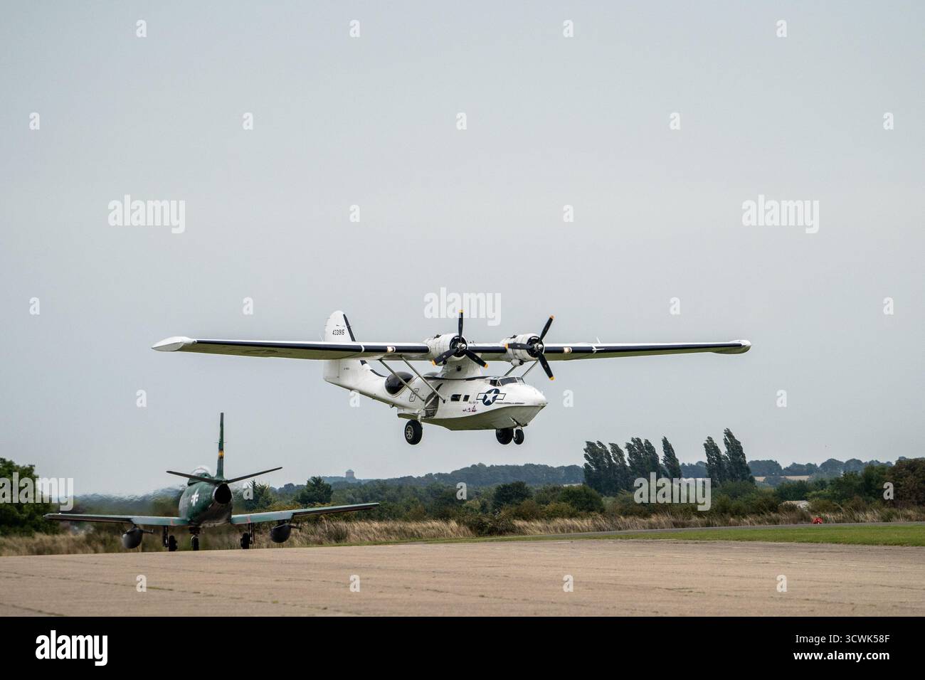 Avion d'hydravion vintage atterrissant à l'aérodrome historique avec avion de chasse au sol Banque D'Images