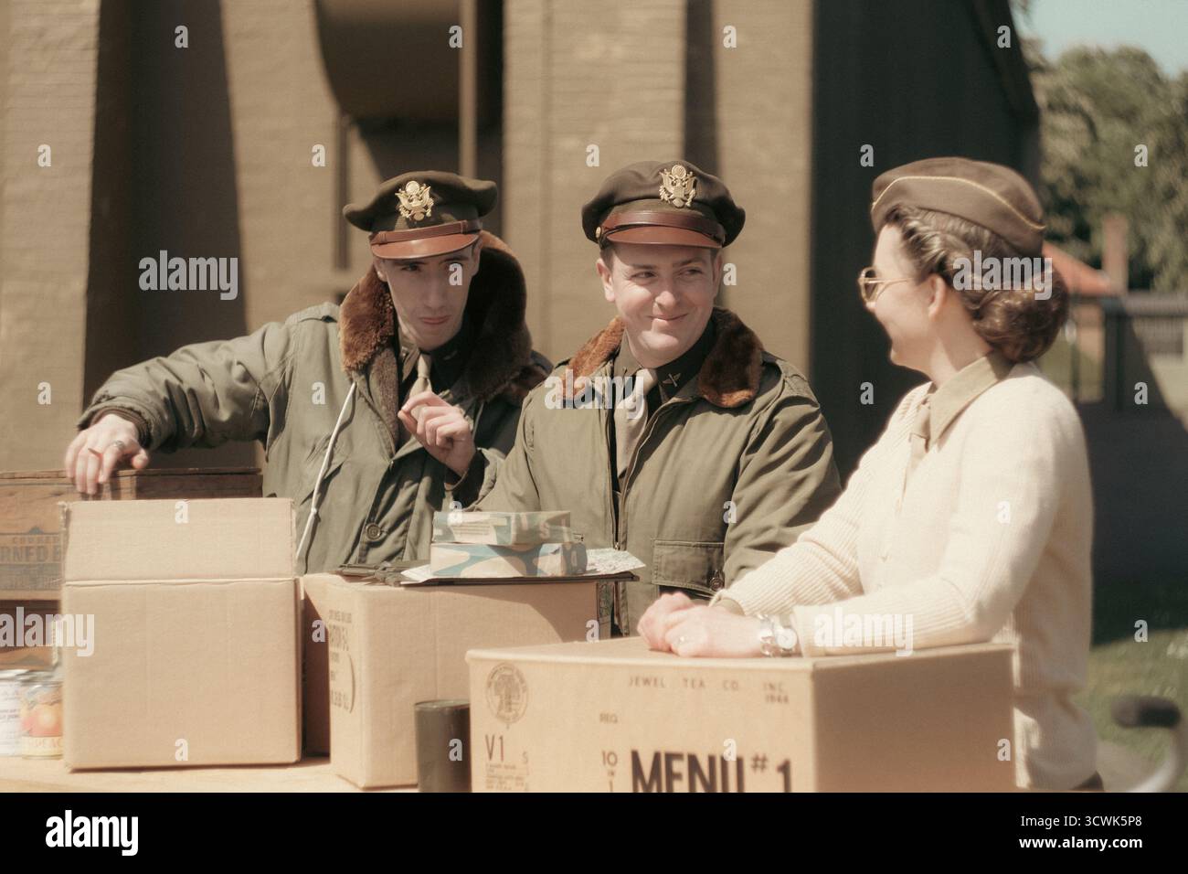 Aviateurs américains de la seconde Guerre mondiale et infirmière avec des boîtes de ration militaires lors de la reconstitution en temps de guerre Banque D'Images