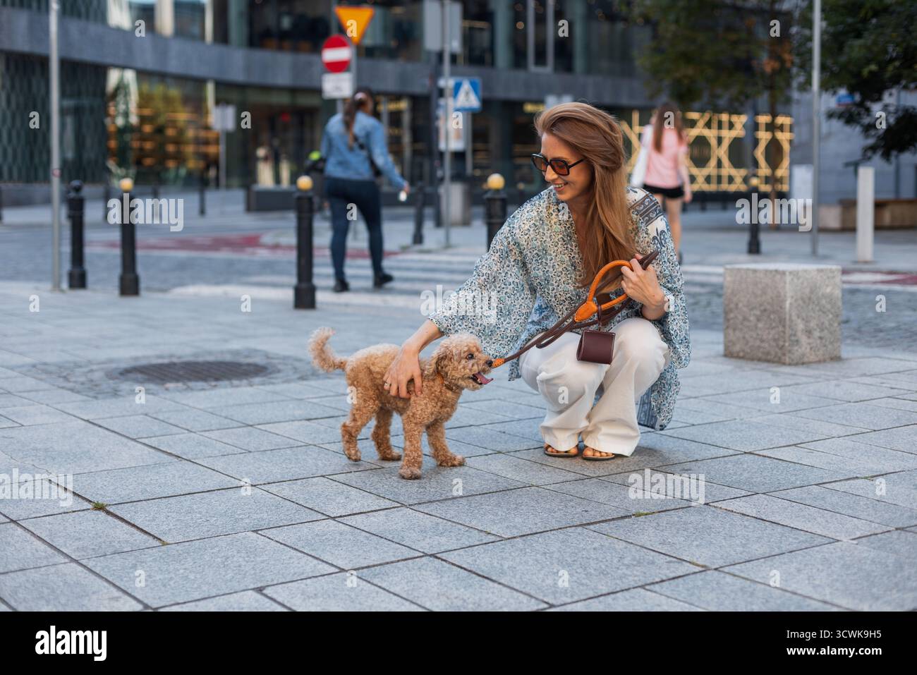 Jeune femme en pantalon blanc ample et Un Crop Top Walking Her Dog dans Une ville moderne. Urban Pet Lifestyle, Fashion-Forward look, et A Joyful Daily Routin Banque D'Images