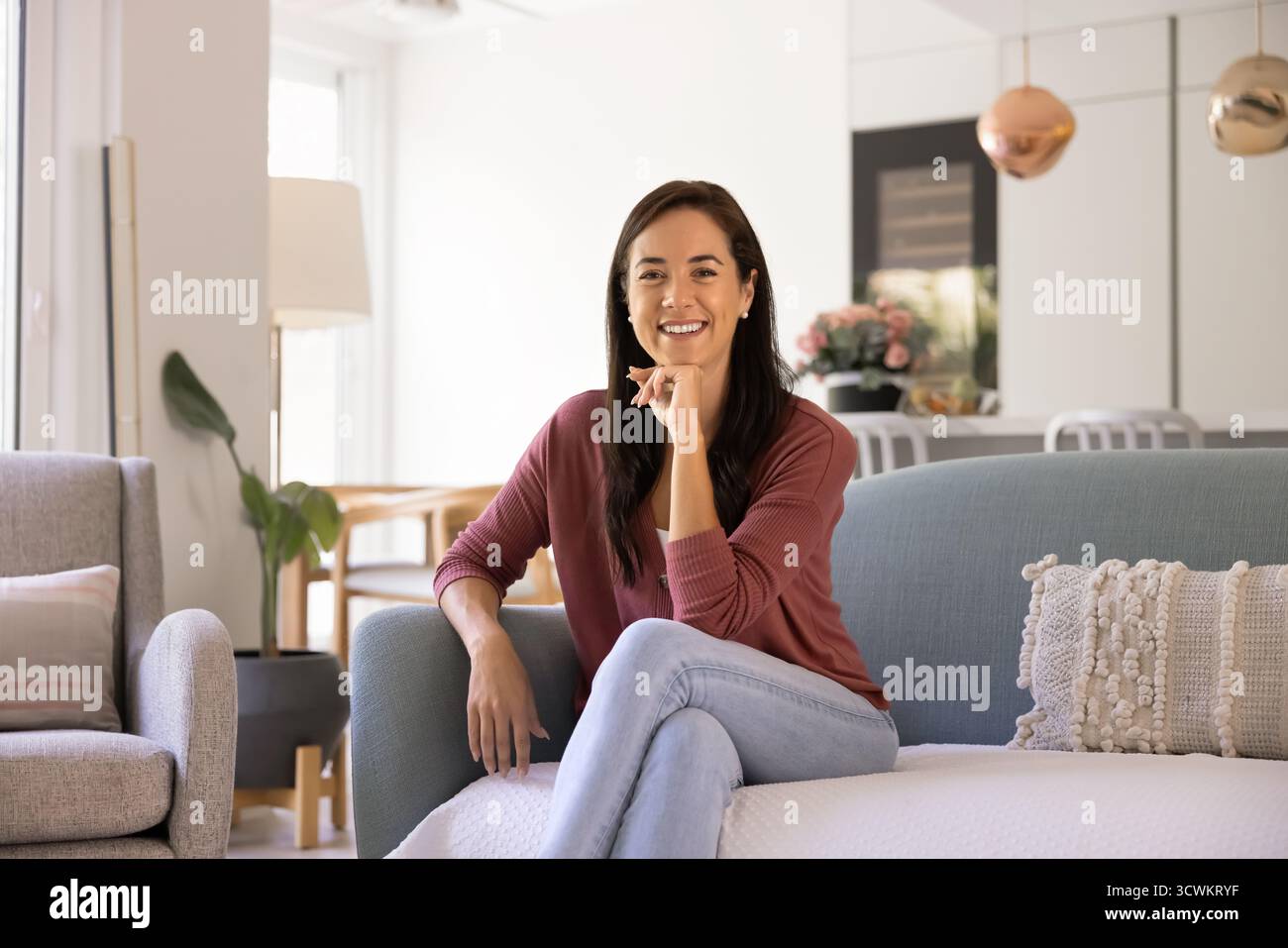 Heureuse femme propriétaire latine confiante assise sur le canapé Banque D'Images