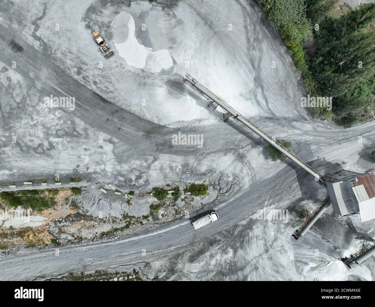 Vue aérienne de l'usine de concassage de granit et de calcaire avec des camions à benne basculante et des excavatrices transformant la pierre brute en agrégats de construction pour le béton et Banque D'Images