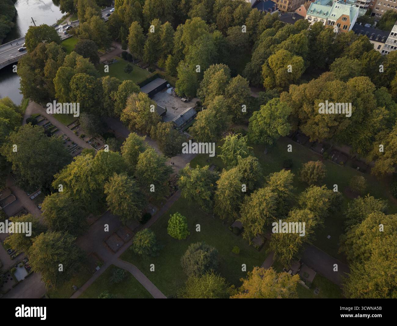 Vue aérienne d'arbres luxuriants projetant de longues ombres sur les sentiers et monuments du vieux cimetière de Malmo, Malmo, Suède. Banque D'Images Vue aérienne d'arbres luxuriants projetant de longues ombres sur les sentiers et monuments du vieux cimetière de Malmo, Malmo, Suède. Banque D'Images