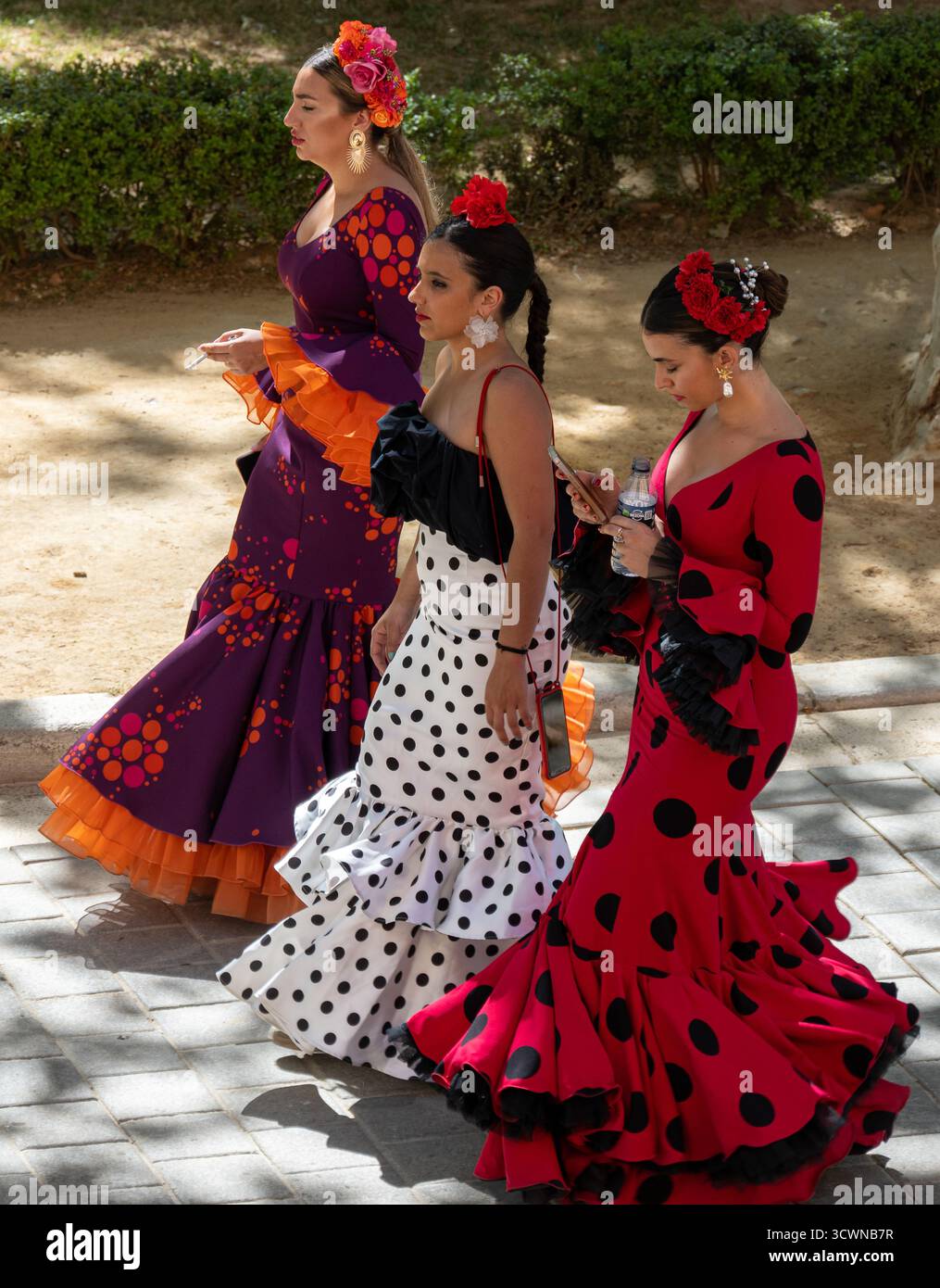 Sevilla, Espagne - 23 avril 23 : trois femmes en robes flamenco colorées marchant ensemble à l'extérieur Banque D'Images