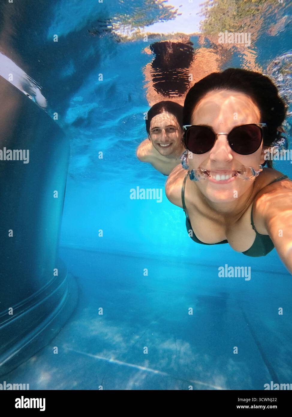 Couple souriant à la caméra prenant un selfie ensemble sous l'eau Banque D'Images