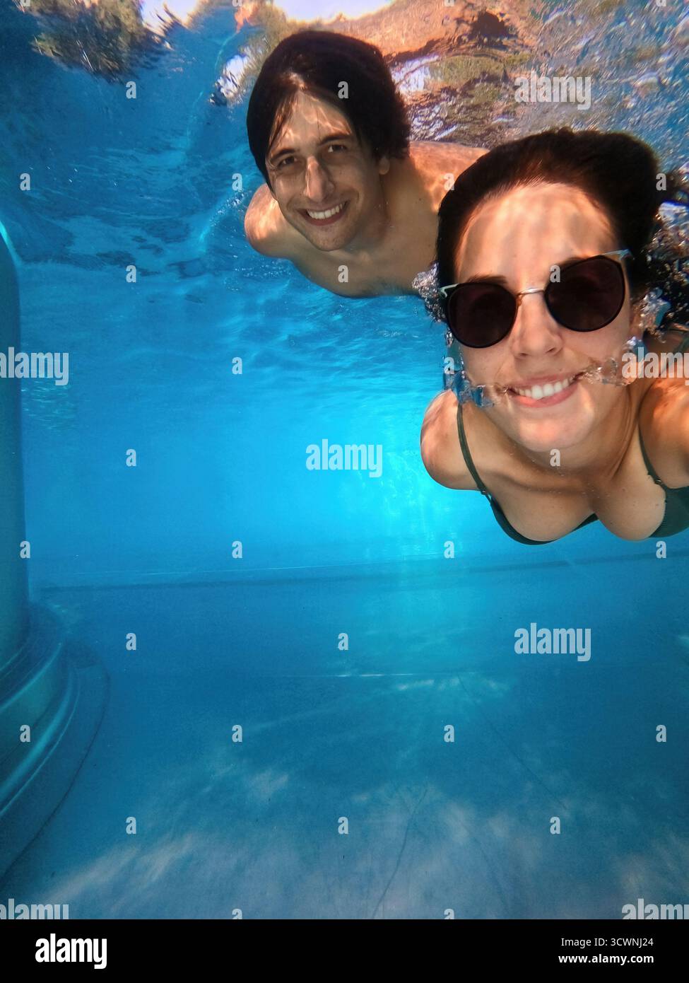 Couple souriant à la caméra prenant un selfie ensemble sous l'eau Banque D'Images