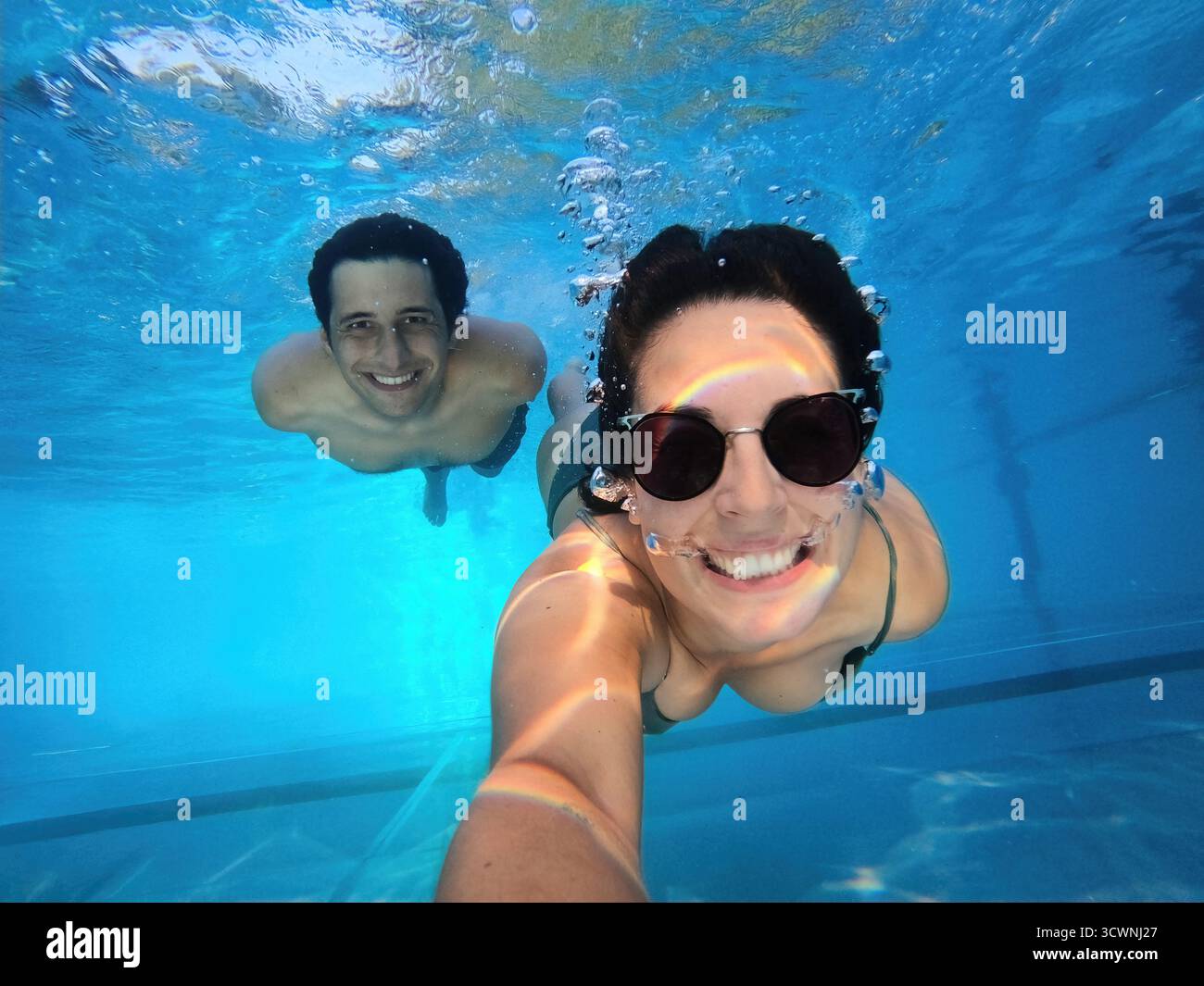 Couple souriant à la caméra prenant un selfie ensemble sous l'eau Banque D'Images