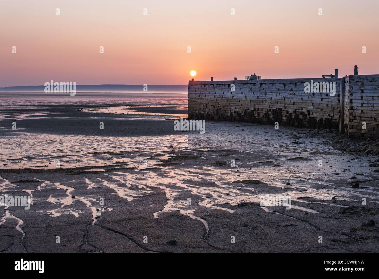 La lumière chaude paisible du coucher de soleil se reflète sur la plage de sable à marée basse Banque D'Images
