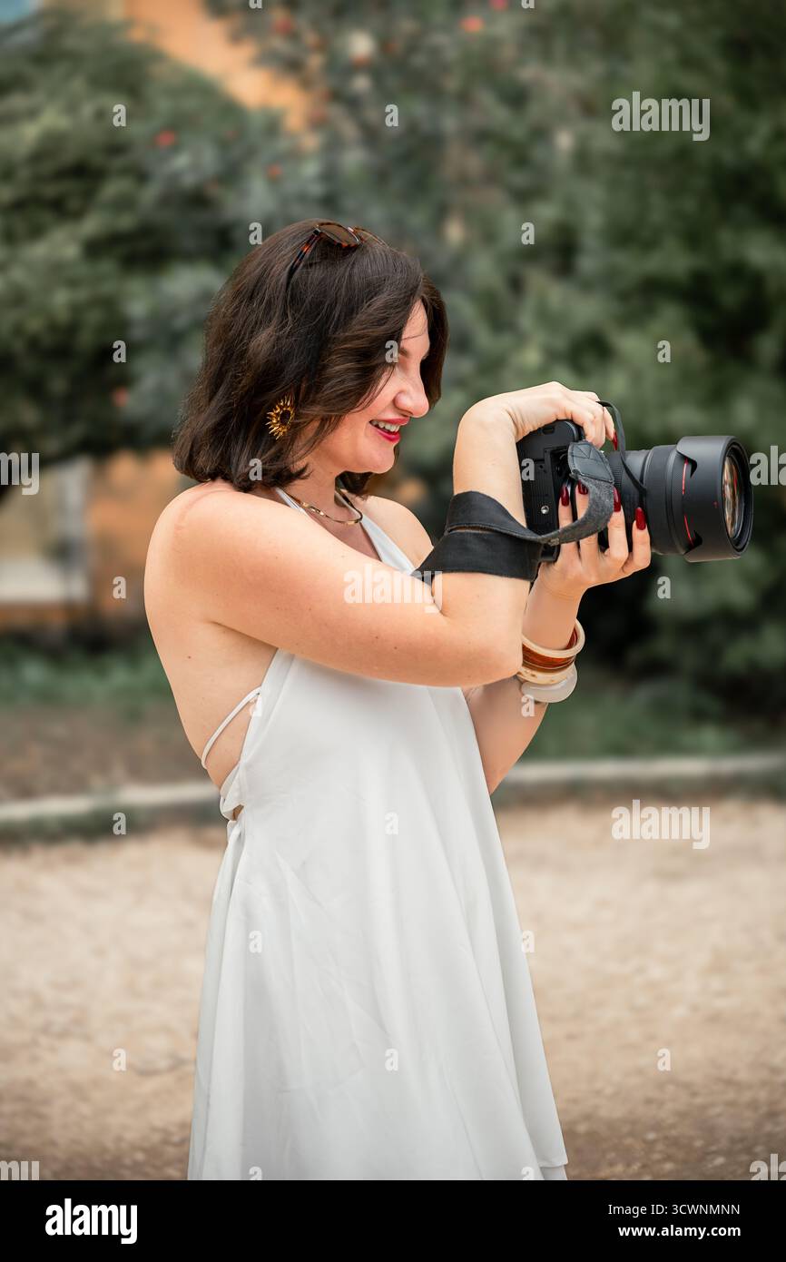 Femme souriante photographe tenant un appareil photo professionnel à l'extérieur Banque D'Images