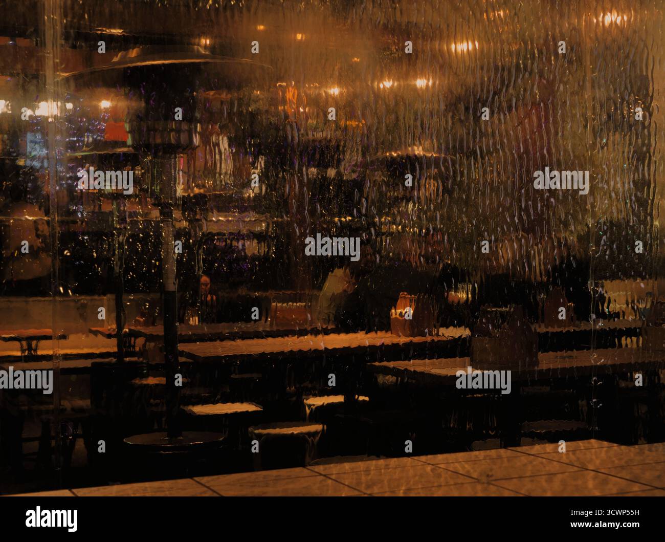 Vue sombre, chaude et sombre d'un intérieur de café confortable à travers le verre texturé sur une nuit humide. Scène atmosphérique et intime. Banque D'Images