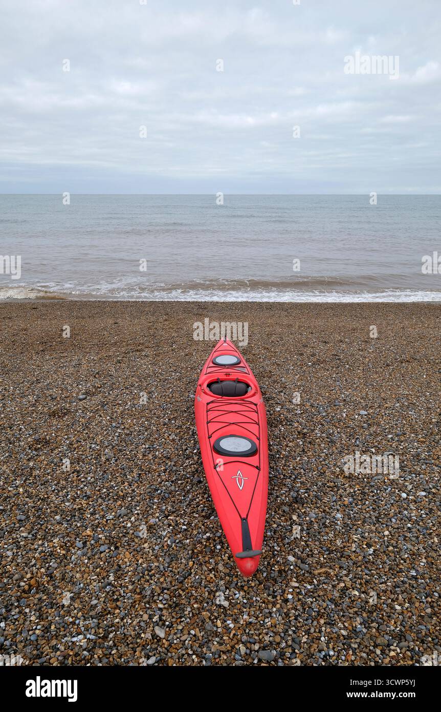 kayak rouge sur la plage de galets de cley-next-the-sea, nord de norfolk, angleterre Banque D'Images