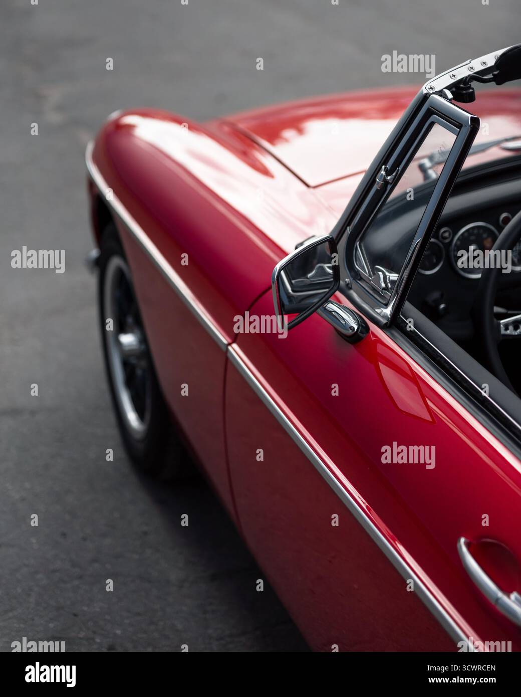 Vieille voiture à toit ouvert avec intérieur en cuir noir. Aile gauche et porte de voiture de sport classique rouge. Mise au point sélective du rétroviseur latéral et du pare-brise Banque D'Images