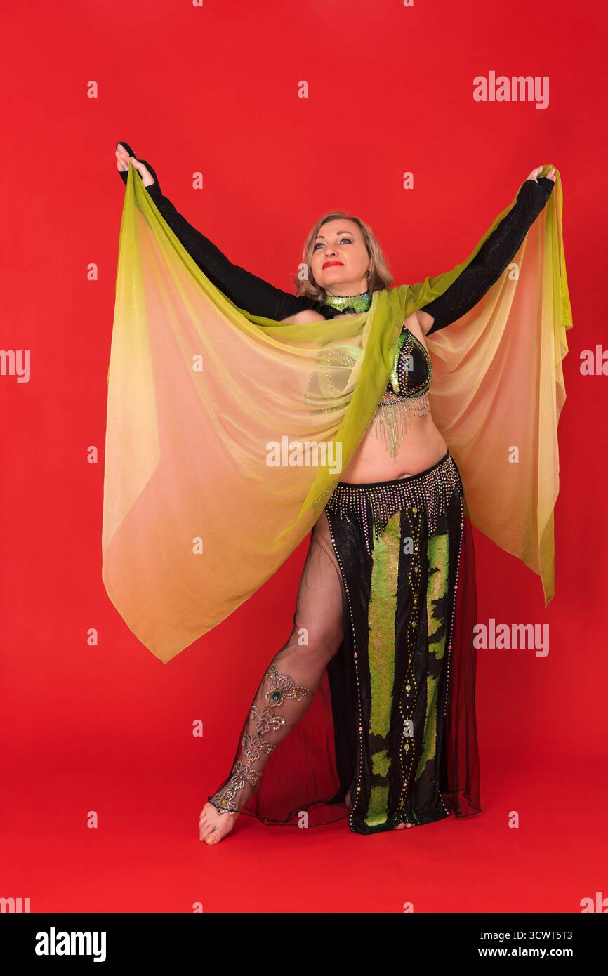 Sensualité femme danseuse du ventre avec les bras vers le haut habillage en costume de scène de danse noir et jaune - jupe longue avec fente, haut de soutien-gorge, boléro, paréo et sans Banque D'Images