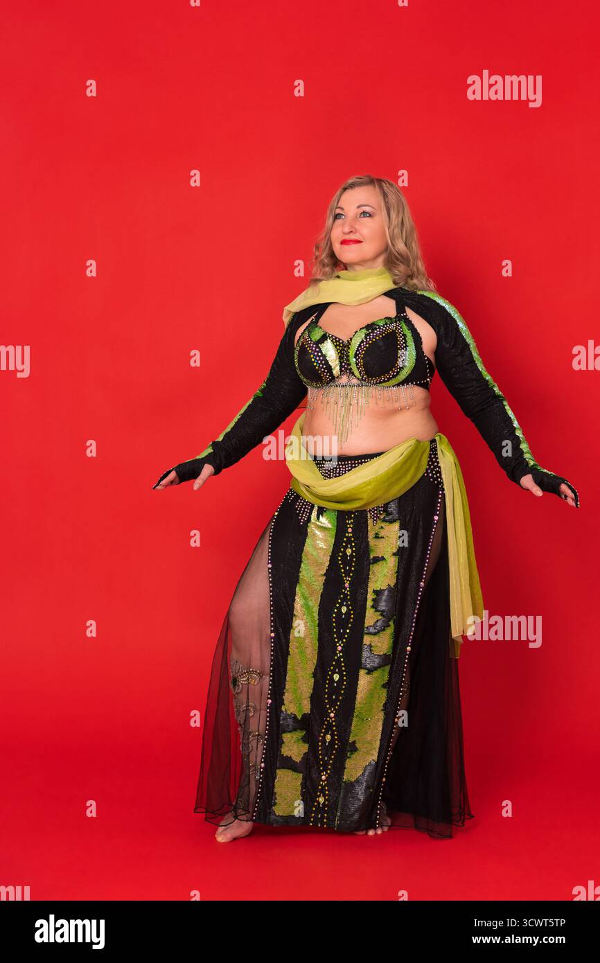 Modèle de mode femme adulte mature vêtu d'une tenue de scène de danse noire et jaune - haut de soutien-gorge, boléro et jupe longue avec fente debout pieds nus en plein l Banque D'Images