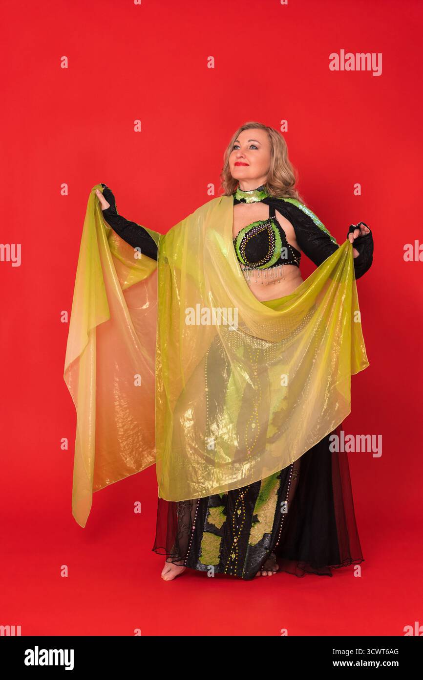 Modèle de mode femme caucasienne heureux habillé en costume de scène de danse noir et jaune - paréo, haut de soutien-gorge, boléro, jupe maxi et elle ne porte aucun foo Banque D'Images