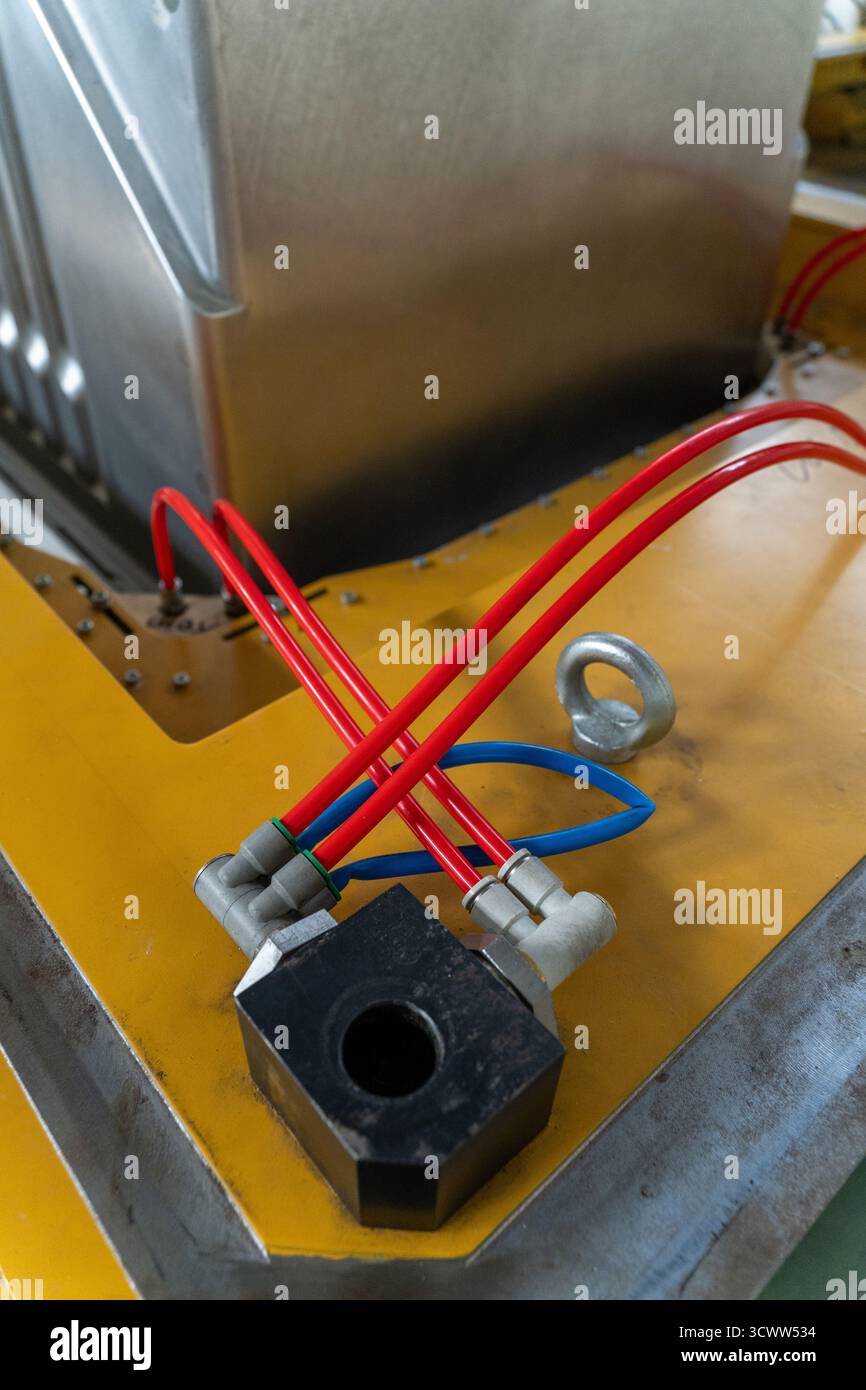 Gros plan d'un système pneumatique sur une machine industrielle utilisée dans une usine de réfrigération. Les flexibles d'air rouge et bleu se raccordent à un bloc métallique sur un jaune Banque D'Images